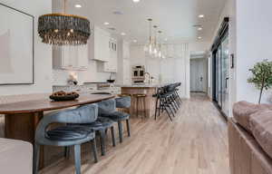 Kitchen featuring recessed lighting, decorative backsplash, a kitchen breakfast bar, a notable chandelier, and white cabinets