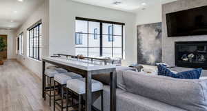 Living room featuring visible vents, baseboards, a glass covered fireplace, recessed lighting, and wood finished floors