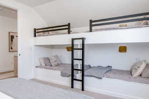 Bedroom with carpet flooring, vaulted ceiling, and baseboards