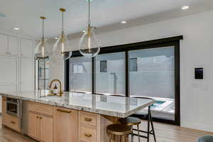 Kitchen featuring light stone countertops, light brown cabinets, light wood finished floors, and a sink