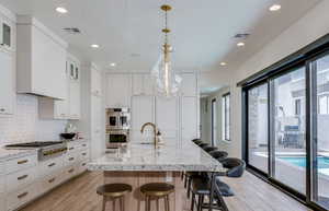 Kitchen with a sink, light wood-style floors, a kitchen breakfast bar, visible vents, and appliances with stainless steel finishes