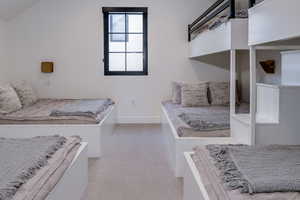 Carpeted bedroom featuring baseboards and lofted ceiling