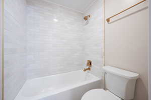 Full bath with ornamental molding, toilet, and bathtub / shower combination