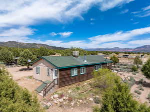 View of front of home featuring a mountain view, central AC unit, and roof with shingles