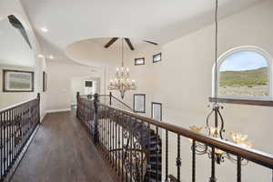 Hallway featuring an upstairs landing, visible vents, baseboards, an inviting chandelier, and wood finished floors
