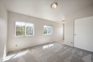 Carpeted spare room with visible vents and baseboards