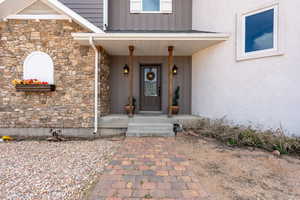 Entrance to property with stone siding, stucco siding, and board and batten siding