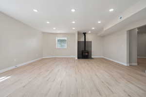 Unfurnished living room featuring visible vents, a wood stove, baseboards, and recessed lighting