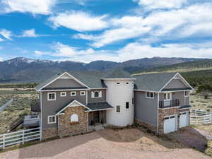 Craftsman-style house featuring a mountain view, driveway, stone siding, and fence