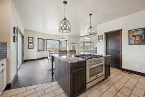 Kitchen featuring light stone countertops, a notable chandelier, high end stainless steel range, baseboards, and dark brown cabinets