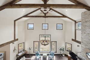 Living room featuring beam ceiling, high vaulted ceiling, and ceiling fan with notable chandelier