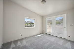 Carpeted spare room with lofted ceiling and baseboards