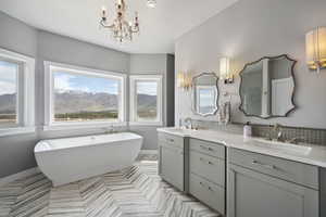 Bathroom with a chandelier, baseboards, double vanity, and a sink