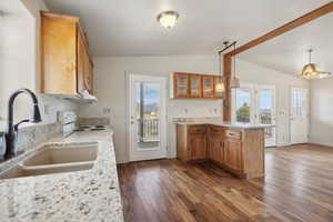 Kitchen with a sink, white electric range, brown cabinetry, vaulted ceiling, and a peninsula