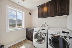 Washroom with cabinet space, washing machine and clothes dryer, light wood-style floors, visible vents, and baseboards