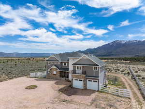 View of front facade featuring fence, driveway, a mountain view, and stone siding