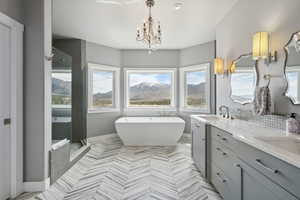 Bathroom with a shower stall, a sink, double vanity, an inviting chandelier, and a freestanding bath