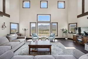 Living area with baseboards, wood finished floors, and a towering ceiling