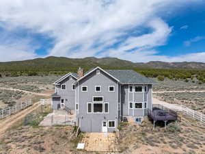 Back of property featuring a chimney, a mountain view, fence, and central AC unit