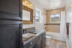 Bathroom with shower / tub combo, visible vents, toilet, wood finished floors, and vanity
