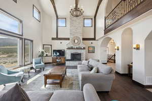Living area featuring a chandelier, a healthy amount of sunlight, baseboards, and a high ceiling