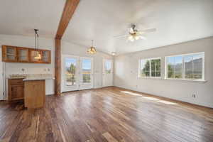 Unfurnished living room featuring dark wood-style floors, baseboards, ceiling fan, and vaulted ceiling