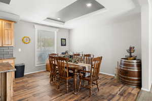 Dining space featuring baseboards, a tray ceiling, dark wood-type flooring, and recessed lighting