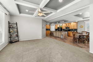 Living area with baseboards, carpet floors, coffered ceiling, and a healthy amount of sunlight