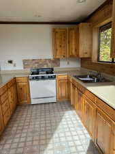 Kitchen with light floors, white gas range oven, light countertops, and a sink