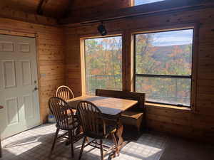 Dining room featuring wooden ceiling, light floors, wooden walls, and vaulted ceiling