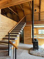 Stairs featuring a wood stove, wooden walls, and carpet flooring