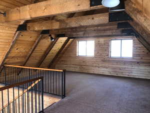Bonus room with wood walls, carpet, vaulted ceiling with beams, and wooden ceiling