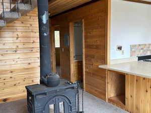 Interior details with carpet, wooden walls, and a wood stove