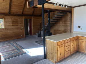 Interior space featuring wooden ceiling, vaulted ceiling with beams, wood walls, light carpet, and light countertops