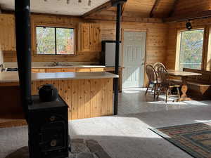 Kitchen with wooden walls, plenty of natural light, a wood stove, and a sink