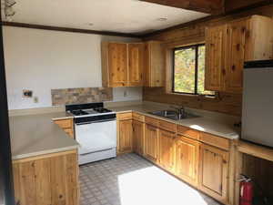 Kitchen with white gas range, a sink, light countertops, and light floors