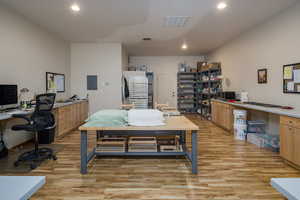 Office space featuring recessed lighting, electric panel, visible vents, and light wood finished floors