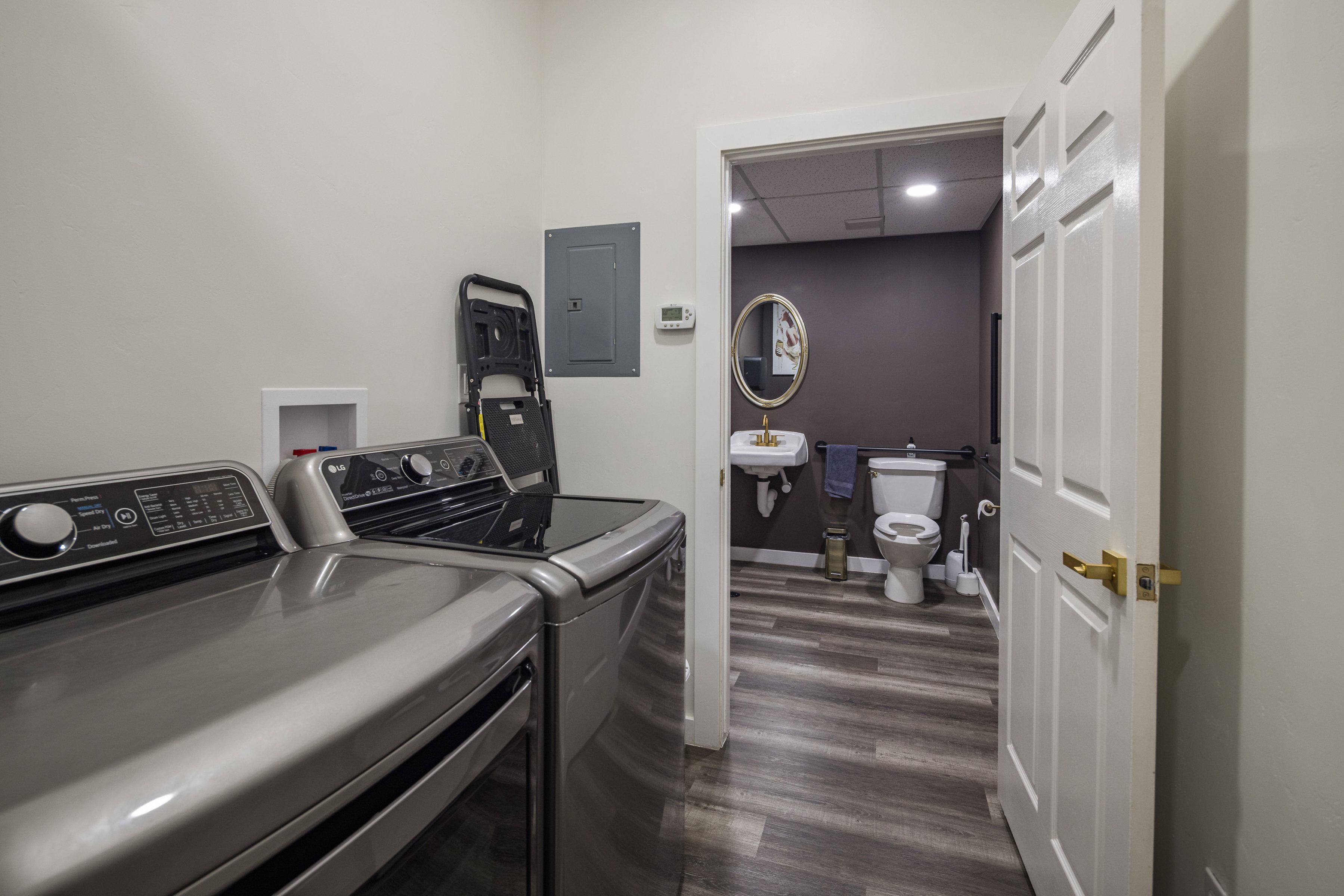 Clothes washing area featuring electric panel, a sink, dark wood-style flooring, separate washer and dryer, and laundry area