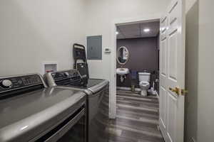 Clothes washing area featuring electric panel, a sink, dark wood-style flooring, separate washer and dryer, and laundry area
