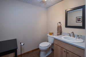 Bathroom featuring baseboards, wood finished floors, toilet, and vanity