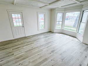Unfurnished room featuring visible vents, wood finished floors, and coffered ceiling