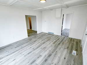 Unfurnished room with baseboards, visible vents, wood finished floors, and coffered ceiling