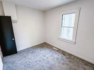 Carpeted spare room with visible vents and baseboards