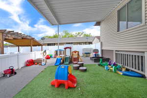 View of playground with a fenced backyard, a yard, and a pergola