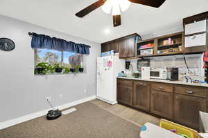 Kitchen with light wood finished floors, open shelves, a ceiling fan, white appliances, and dark brown cabinets