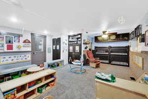 Recreation room with a ceiling fan and carpet floors