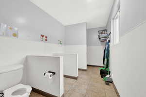 Bathroom featuring toilet, tile patterned flooring, and baseboards