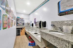 Bathroom with recessed lighting, wine cooler, tasteful backsplash, double sink, and wood finished floors