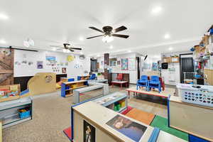Recreation room featuring a barn door, ceiling fan, and recessed lighting