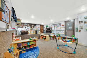 Recreation room with a barn door, recessed lighting, and carpet flooring